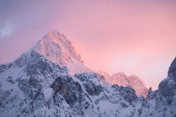 Beautiful close up shot of a pink glowing Mountain top in the Alps at sunset while wind is blowing...