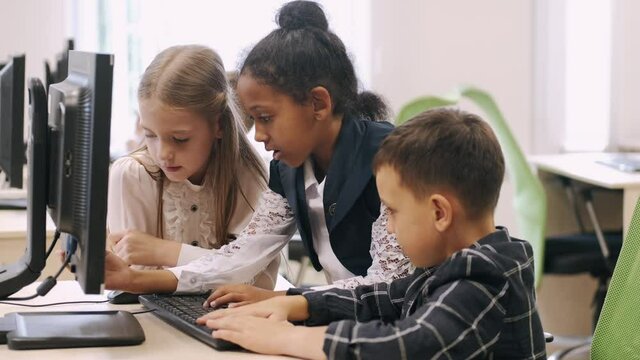 Technologies and studying concept. Schoolchildren working with computer on IT classes at school.