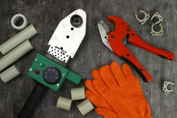 Soldering iron for PVC pipes, scissors, plastic pipes. Tools for plumbing work on a gray background