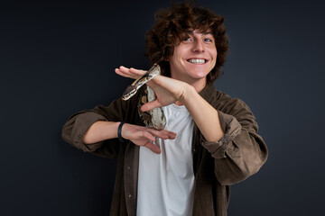 python snake coiling around mans hand, cheerful guy enjoys, likes exotic animals