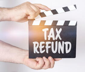 On a white background, a man holds a clapperboard in his hands on which it is written - TAX REFUND