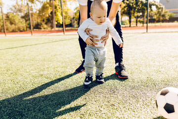 young mom with son play soccer on the field, outdoors