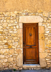 Fototapeta na wymiar An old wooden door with a metal knocker and a stone frame and wall