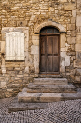 Fototapeta na wymiar A very old vintage door with a stone wall and a white shuttered window