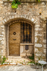 A vintage medieval wooden door with a stone wall and a white steal chair