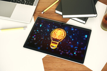 Modern digital tablet monitor with creative light bulb hologram with human brain, idea and brainstorming concept. Top view. 3D Rendering