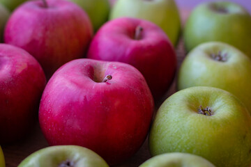 Green and red apples stand on a wooden surface