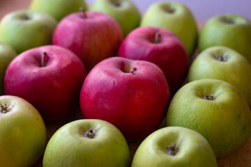 Green and red apples stand on a wooden surface