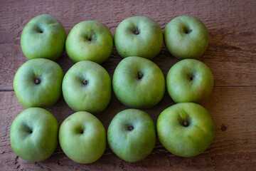 Green apples stand on a wooden surface