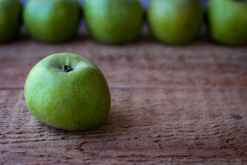 Green apples stand on a wooden surface