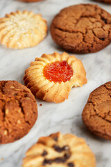 Different types of shortcrust pastry cookies: with chocolate, jam, sesame seeds, oatmeal. Assorted cookies on a light background, top view