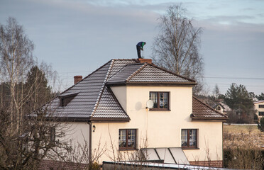 A chimney sweep cleans the chimney on the roof of a detached house