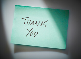 green note paper with inscription thank you on the white board