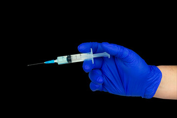 Hand in blue glove holding syringe with copy space. Syringe with sharp needle in hand. Medical treatment concept. Laboratory backgrouund.  Vaccination concept, isolate black background