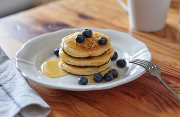 Delicious homemade cheesecakes drizzled with honey and sprinkled with fresh blueberries, on a wooden background