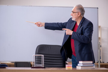 Old teacher physicist sitting in the classroom
