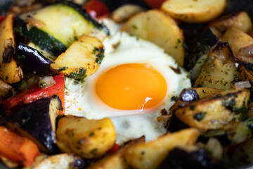 Serve one fried egg with baked vegetables, sausage. Round bright yellow yolk in the center.