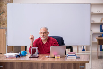 Old teacher physicist sitting in the classroom