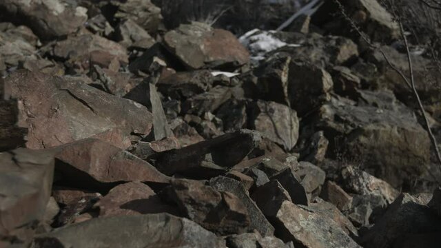 A  medium closeup shot of  a mysterious man in boots going down the mountain 