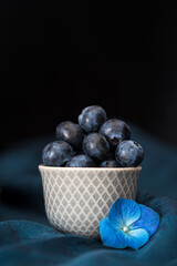 blueberries in a white bowl and blue flower