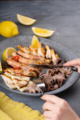 Woman eating Seafood assorted platter - Prawn Shrimp, Squid, Octopus mini, lemon