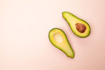 Halved and whole avocados on pink table