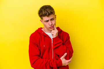 Young caucasian man isolated on yellow background contemplating, planning a strategy, thinking about the way of a business.