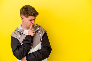 Young caucasian man isolated on yellow background looking sideways with doubtful and skeptical expression.