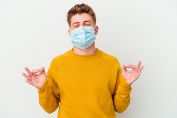 Young man wearing a mask for coronavirus isolated on white background relaxes after hard working day, she is performing yoga.