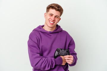 Young caucasian man holding a gamepad isolated on white background laughing and having fun.