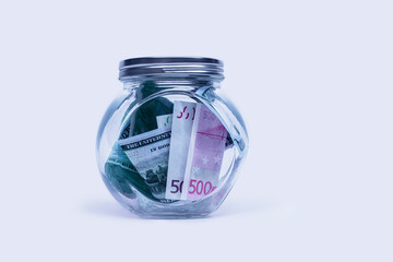 Glass piggy bank with dollars and euro on a white background.