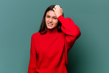Young Indian woman isolated on blue background forgetting something, slapping forehead with palm...