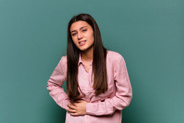 Obraz premium Young Indian woman isolated on blue background having a liver pain, stomach ache.