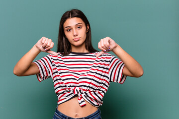 Young Indian woman isolated on blue background showing a dislike gesture, thumbs down. Disagreement...