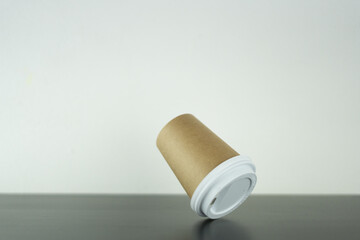 a takeaway paper cup in mid-air is falling on the table upside down.
