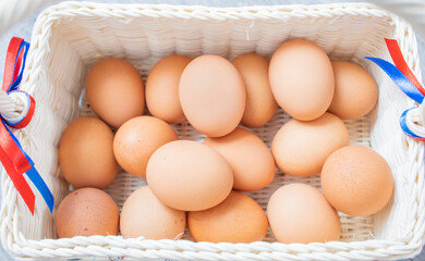 Uncooked organic eggs, a fresh raw ingredient from a farm in a white wicker basket with natural light. Nature healthy food for diet, a product from grocery store. Symbol of Easter holiday. Top view.