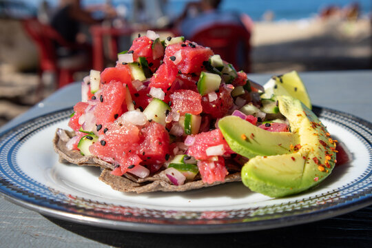 Tuna Ceviche Tostada served with avocado and lime on the beach in Mexico