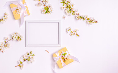 Gift boxes, blossoming cherry branches with a frame for text on a white background with copy space.