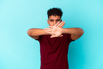 Young african american curly man isolated on blue doing a denial gesture