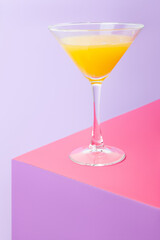 Glass of cocktail with lemon on colorful table