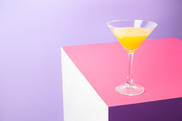 Glass of cocktail with lemon on colorful table