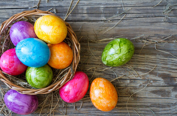Colorful easter eggs in basket on old wooden boards background