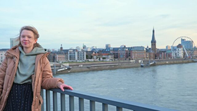 [4k] panning shot accross cityscape of D&uuml;sseldorf toward a casual woman on a bridge over the river rhein