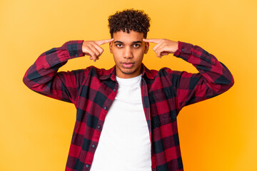 Young african american curly man isolated on purple focused on a task, keeping forefingers pointing head.