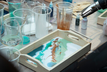 workshop on painting wooden pallets with epoxy resin. Plastic cups with colored resin, on the table, close-up. Painstaking work with gloves. Hobbies, entertainment