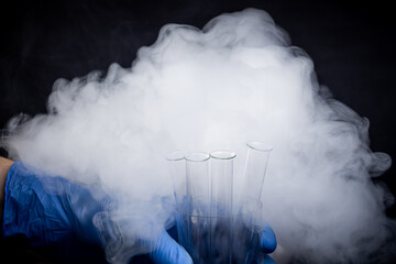 person holding laboratory test tube with steam around it isolated over blue background. research glassware. copy space. research concept
