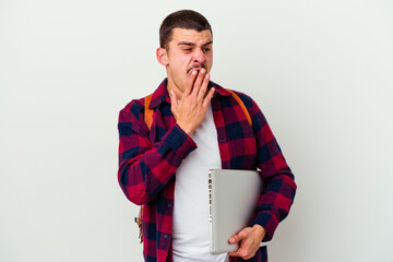 Young caucasian student man holding a laptop isolated on white background yawning showing a tired gesture covering mouth with hand.