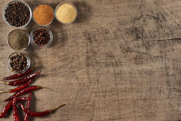 dried red pepper and bowls of spices on a wooden surface