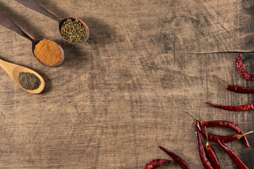 dried red pepper and wooden spoons with spices  on a wooden surface