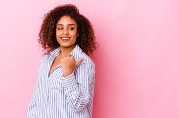 Young african american woman isolated on pink background points with thumb finger away, laughing and carefree.